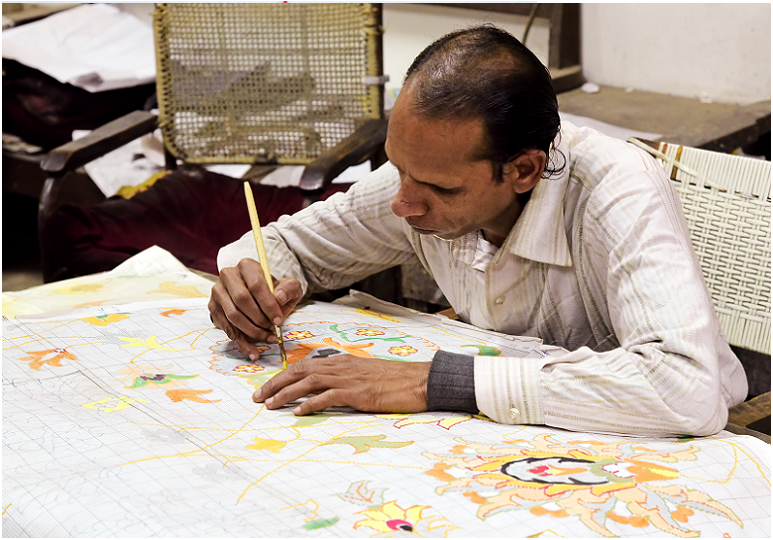 L'homme indien crée une conception de tapis de laine. Ces motifs de conception ont été transmis de génération en génération à Agra, en Inde.